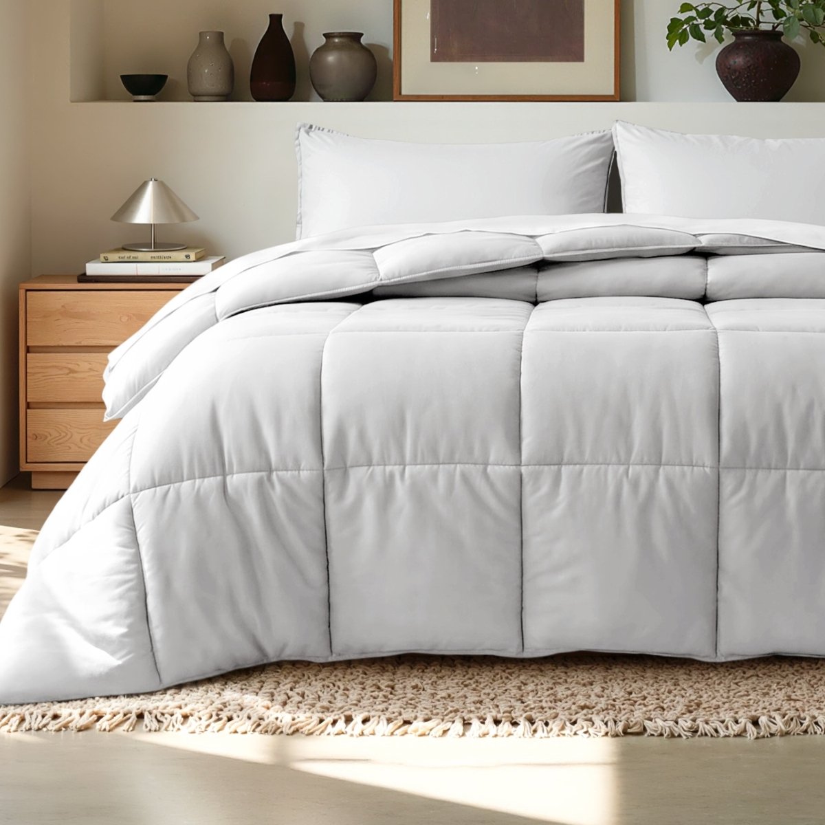 Comforter on a bed in a bedroom setting with a wooden nightstand and decorative items.