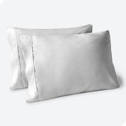 Two pillows on a white background with grey pillowcases on them