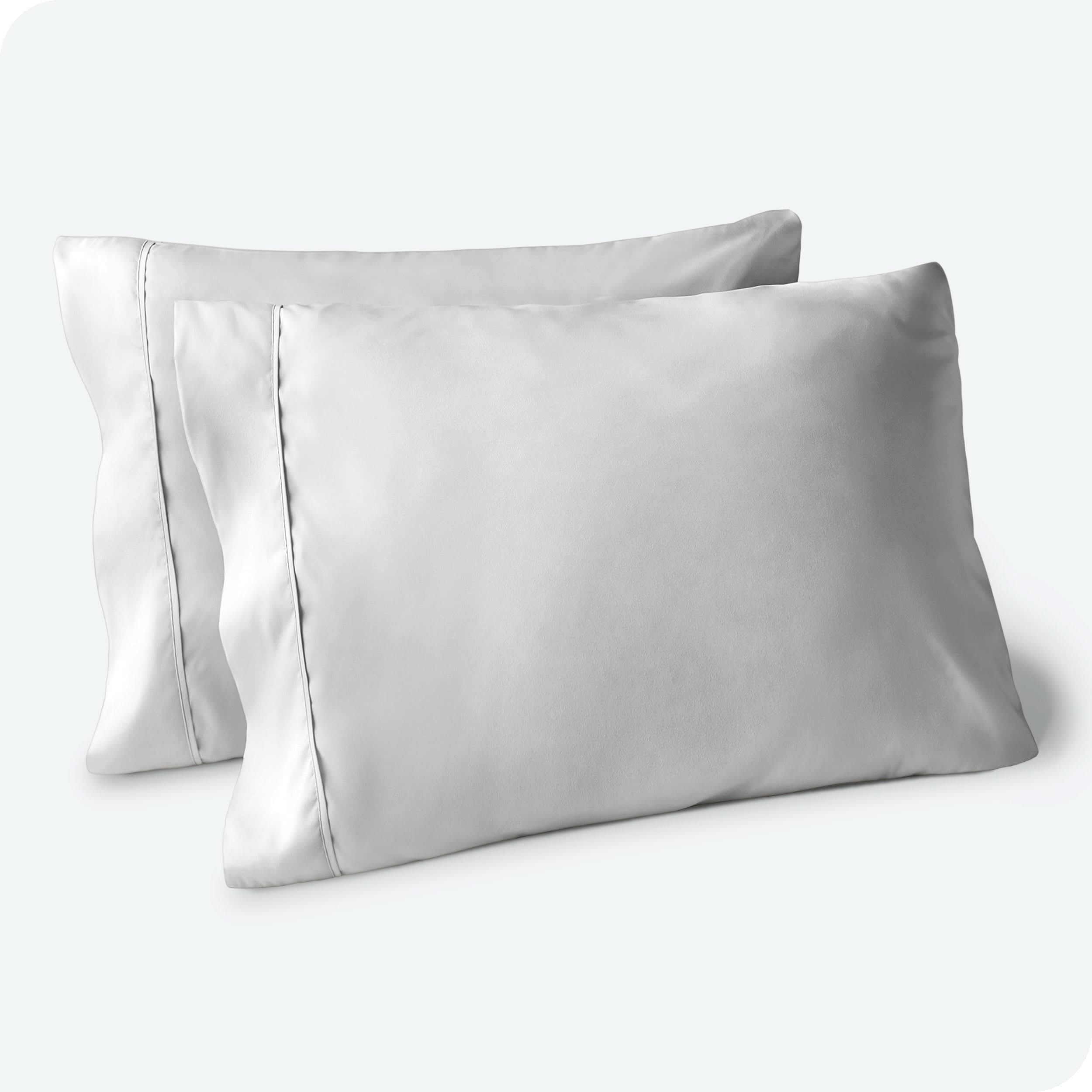 Two pillows on a white background with grey pillowcases on them