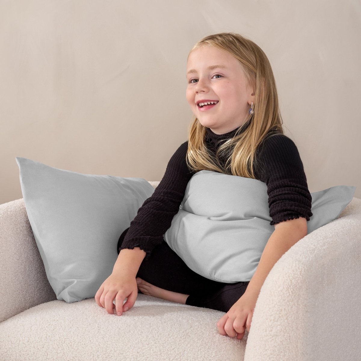 A child sitting while holding a microfiber pillowcase covered pillow