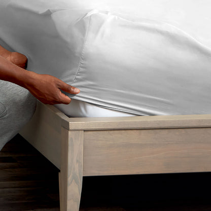 Person adjusting a fitted sheet on a mattress
