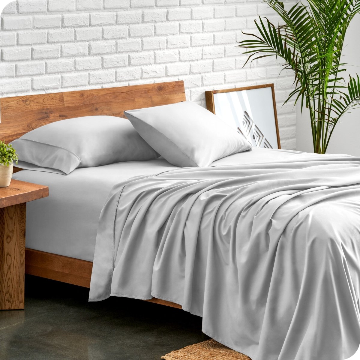 Bed with microfiber sheets against a white brick wall