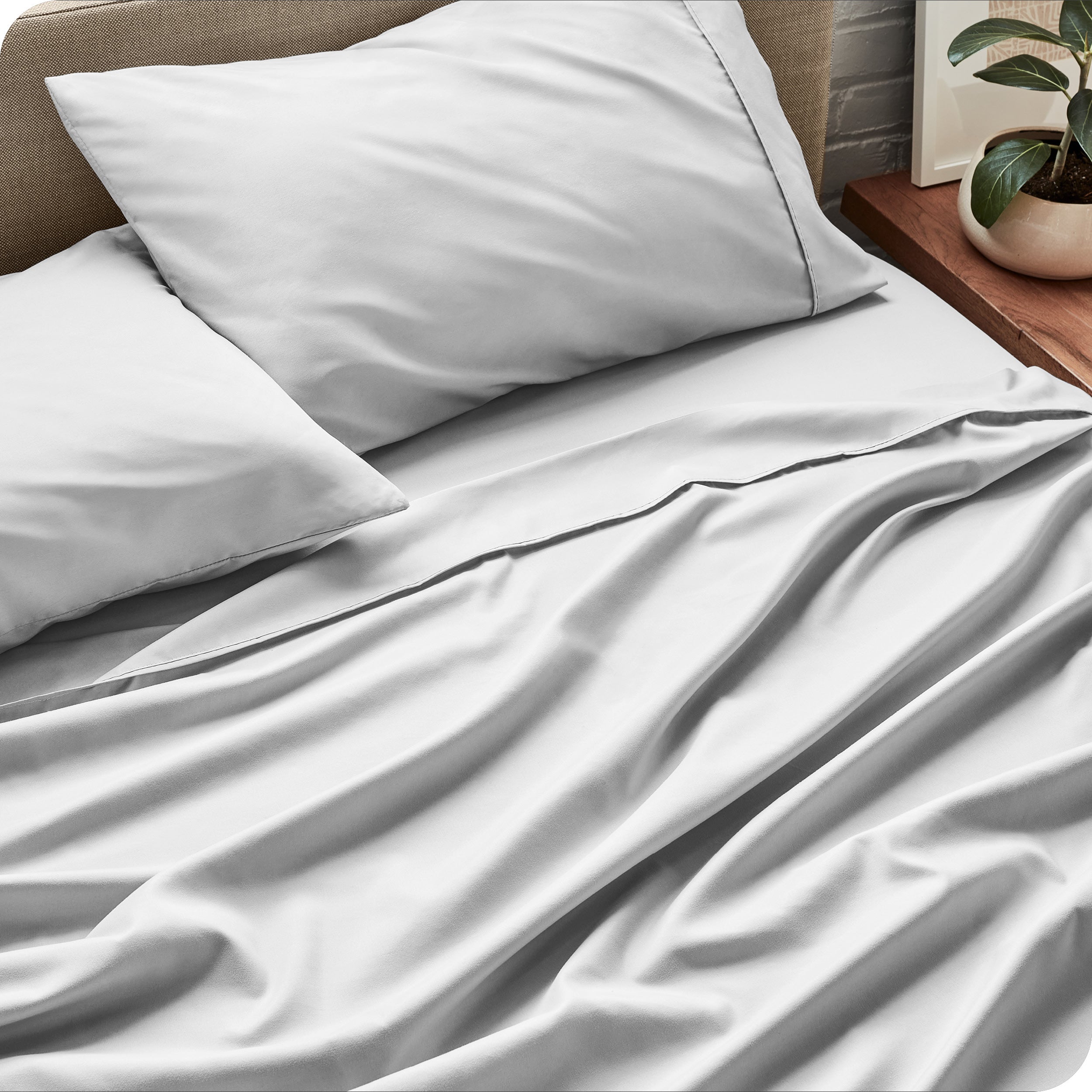 Sheet set on a bed with pillows and a plant in the background