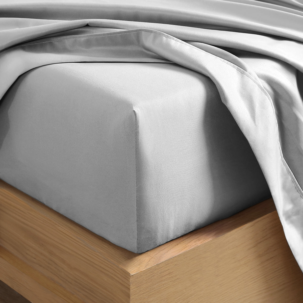 Close up of the corner of a mattress with a fitted sheet and flat sheet on it