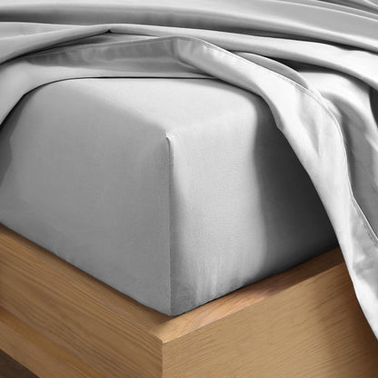 Close up of the corner of a mattress with a fitted sheet and flat sheet on it