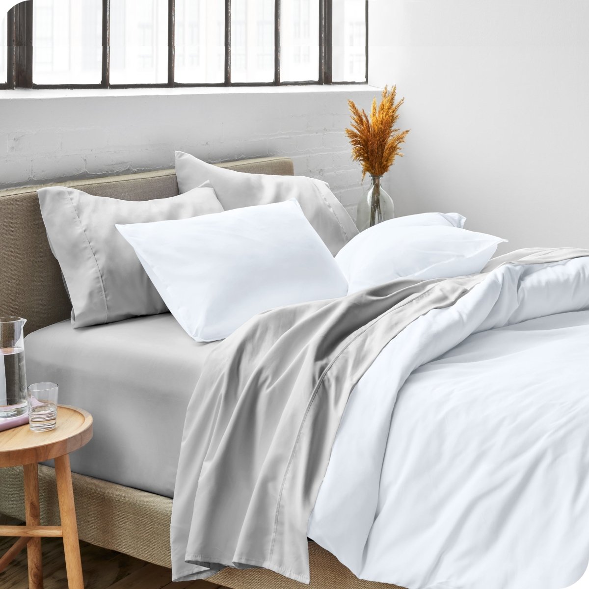 A side view of a bed made with microfiber sheets and a white duvet cover