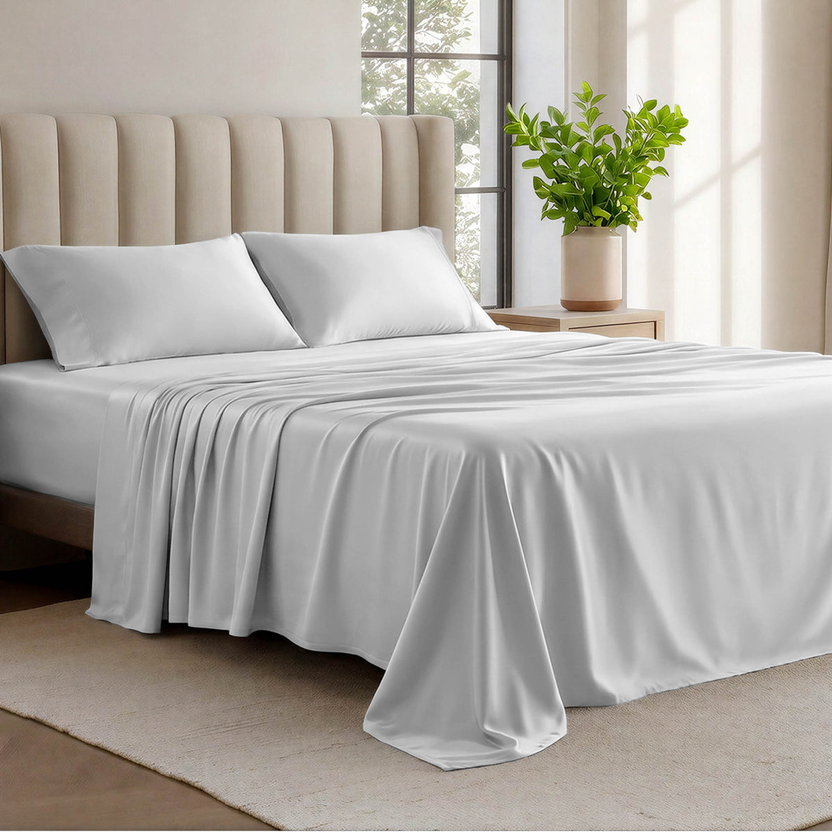 Organic cotton jersey sheets on a bed with a wicker headboard in a room with plants and a lamp.