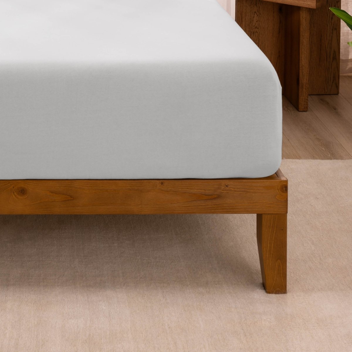Fitted sheet on a wooden bed frame with a neutral background
