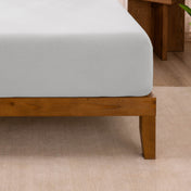 Fitted sheet on a wooden bed frame with a neutral background