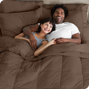 A couple is lying in bed with a comforter and sheets over them