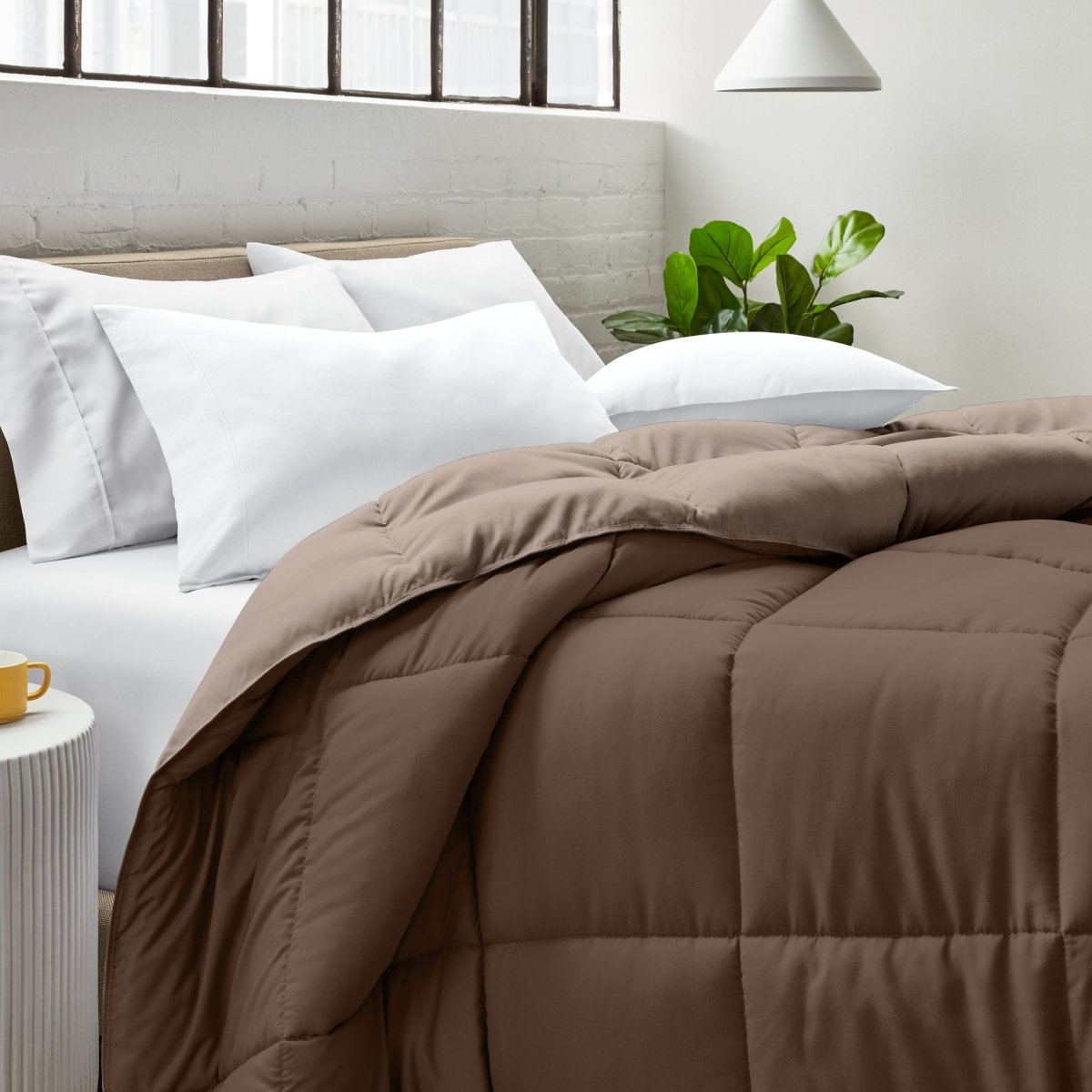 Bed with comforter and white pillows in a bright bedroom setting.
