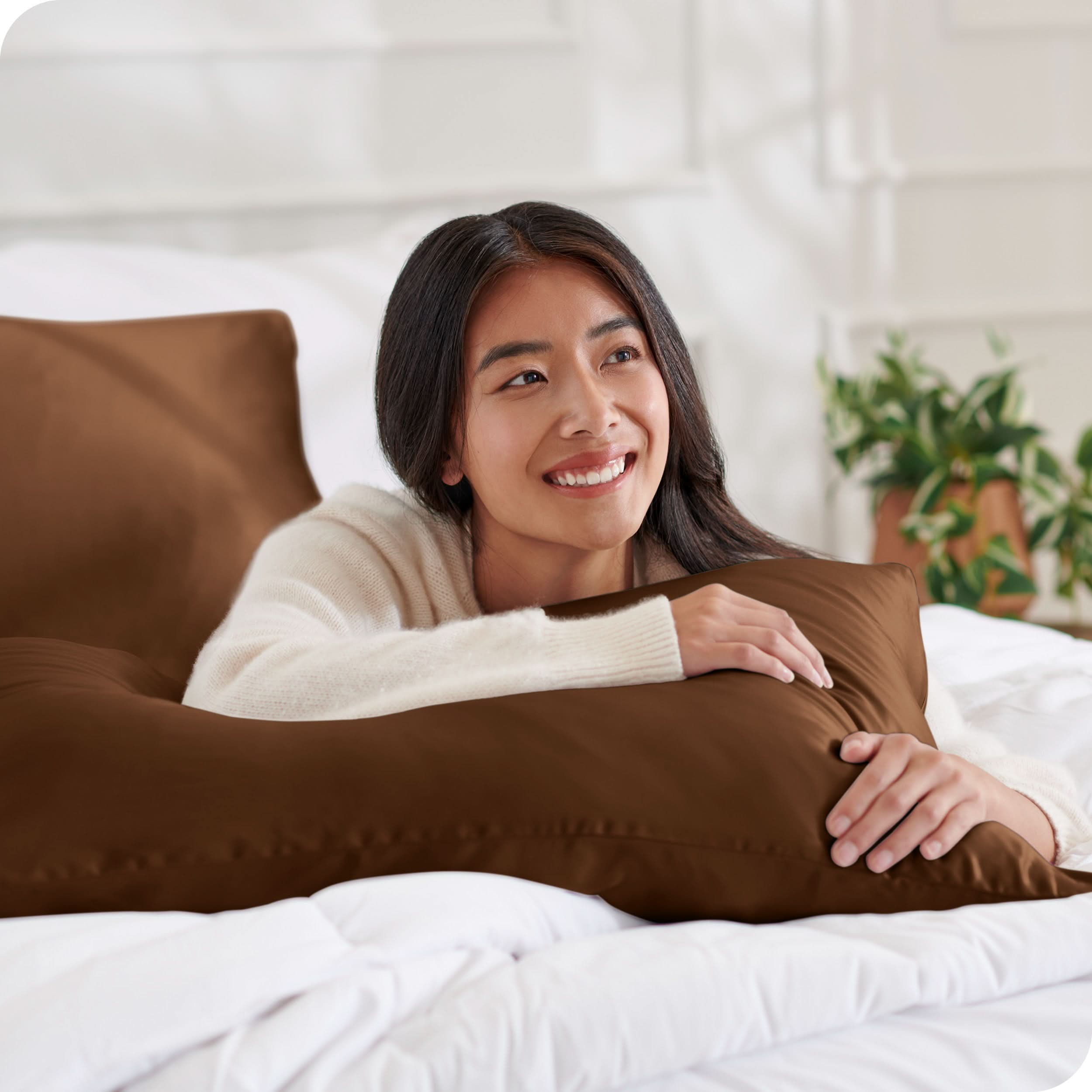 A woman on a bed with a silk pillowcase covered pillow