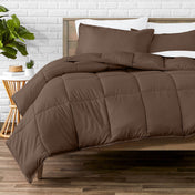 Comforter set on a bed with a white brick wall and plant in the background