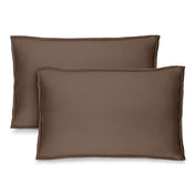 Two brown pillow shams on pillows standing up with one behind the other