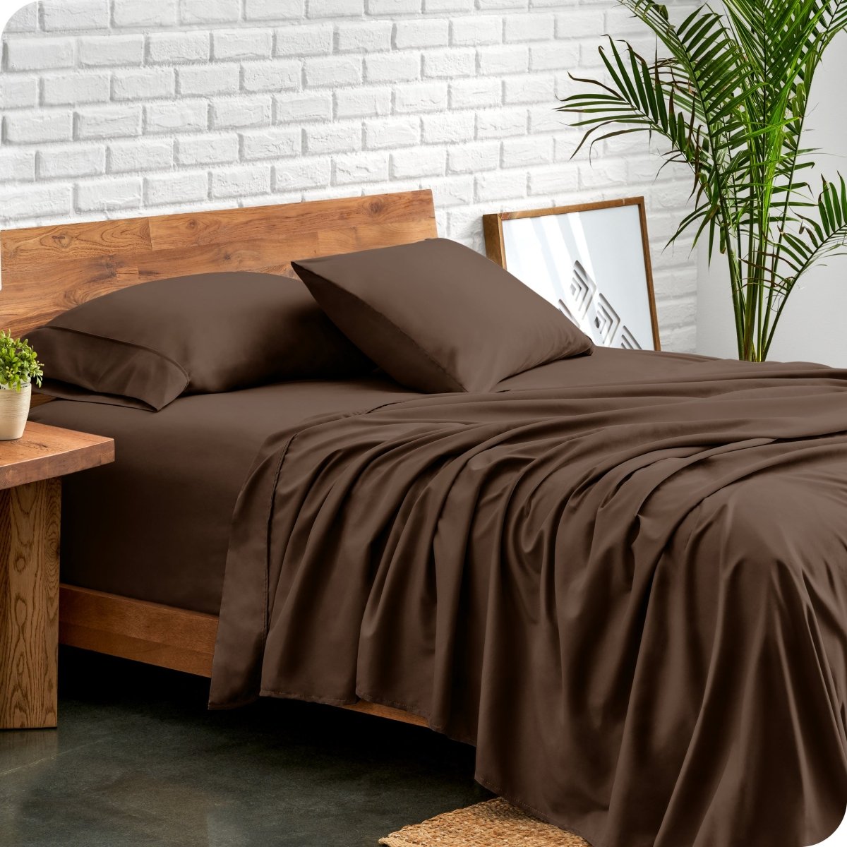 Bed with microfiber sheets against a white brick wall