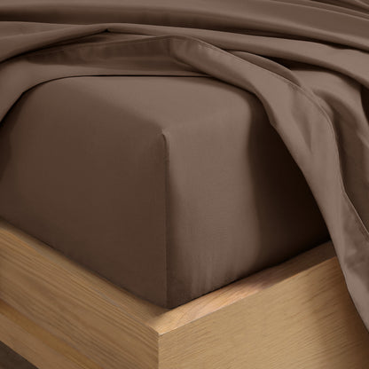 Close up of the corner of a mattress with a fitted sheet and flat sheet on it