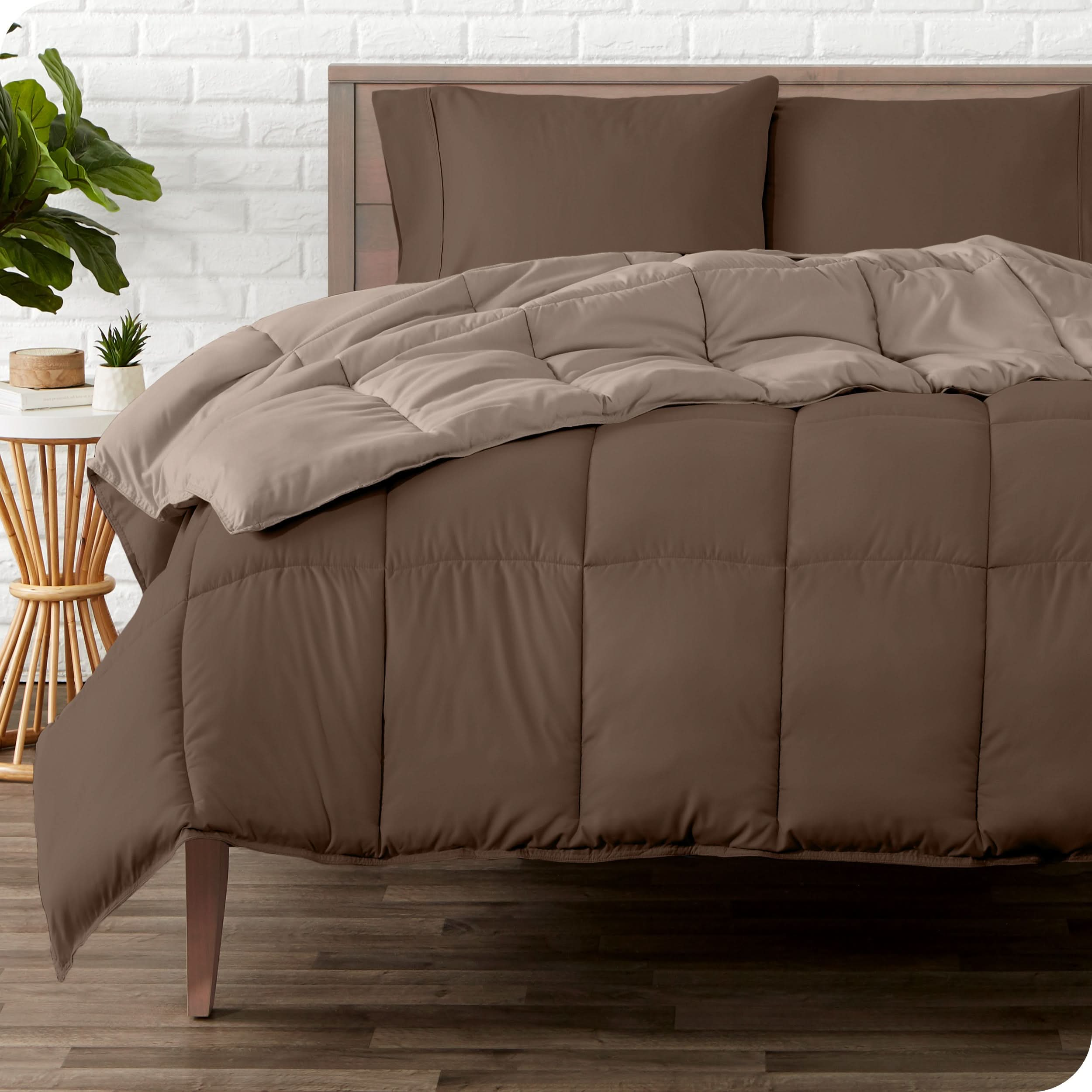 A wooden bed frame with a reversible comforter and sheet set on the mattress