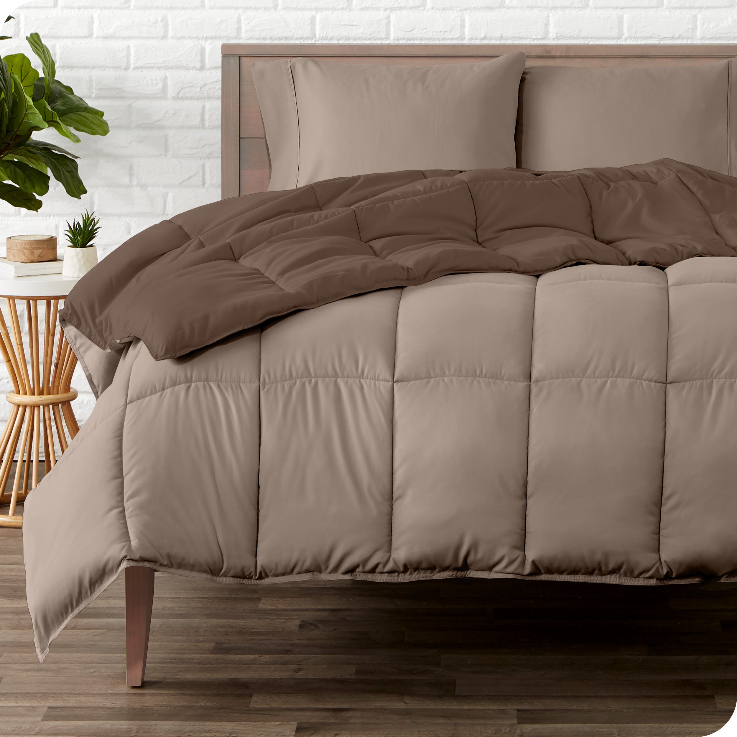 A wooden bed frame with a reversible comforter and sheet set on the mattress
