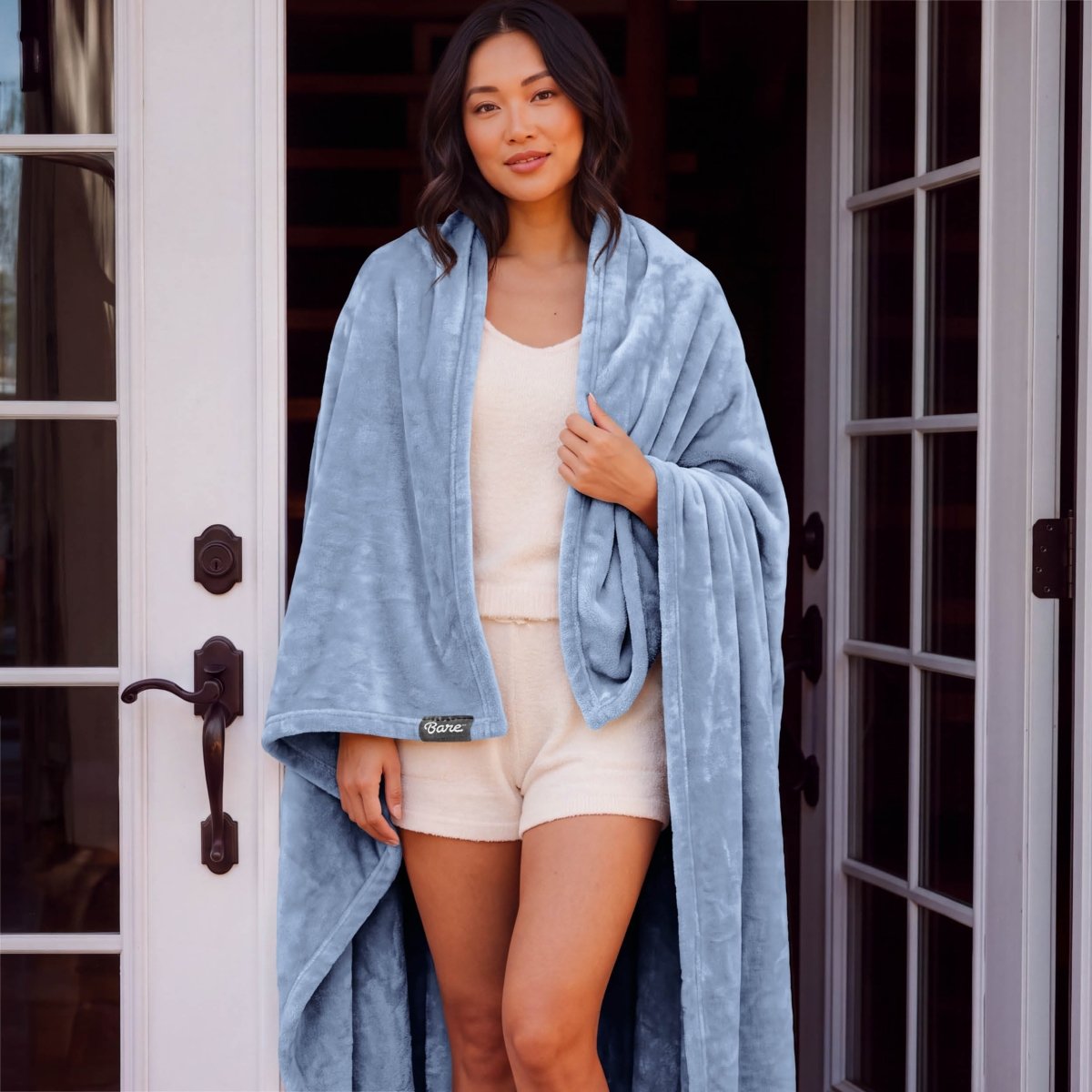 A woman standing with a microplush blanket wrapped around her