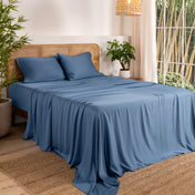 Bamboo sheets on a bed in a bedroom with plants and a lamp.