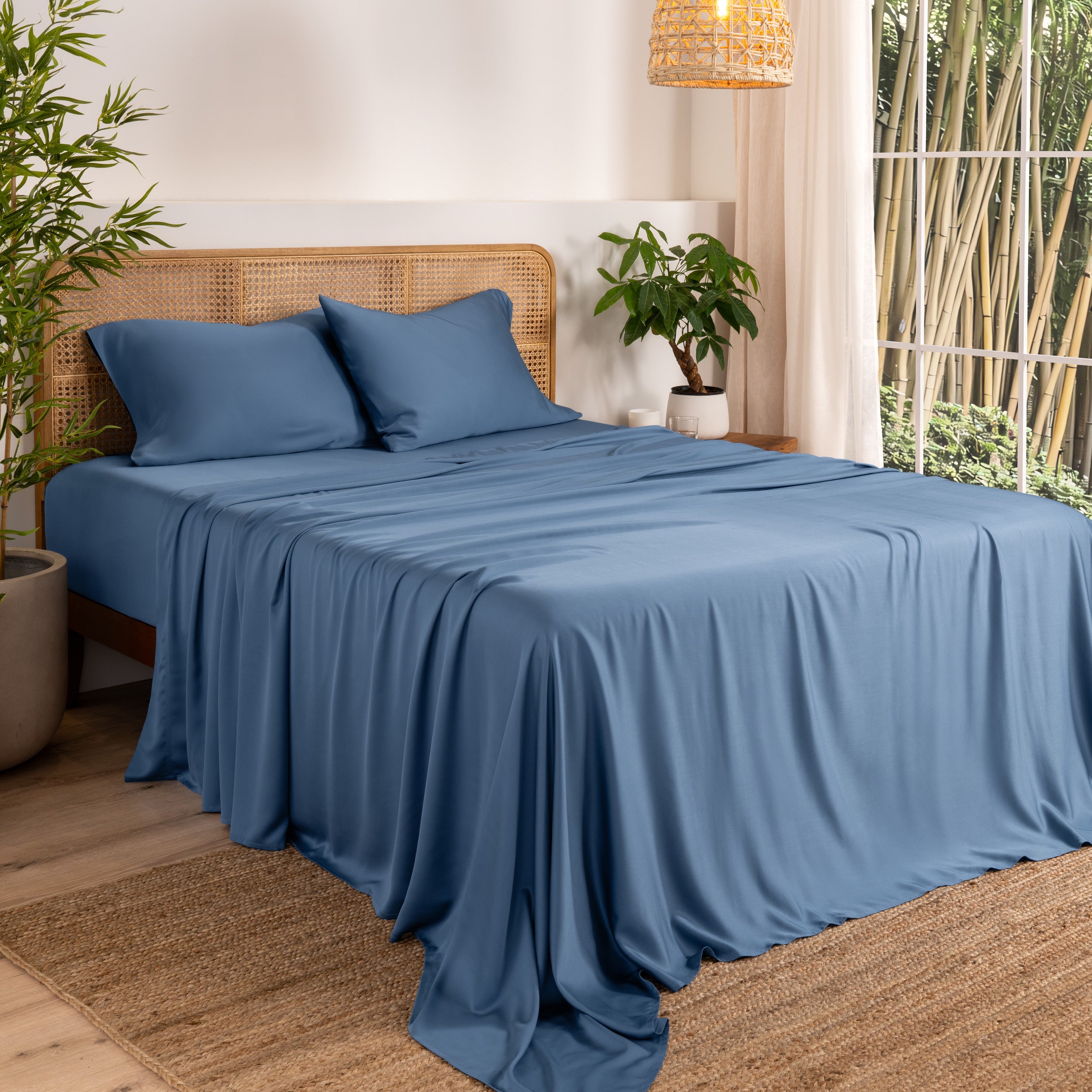 Bamboo sheets on a bed in a bedroom with plants and a lamp.