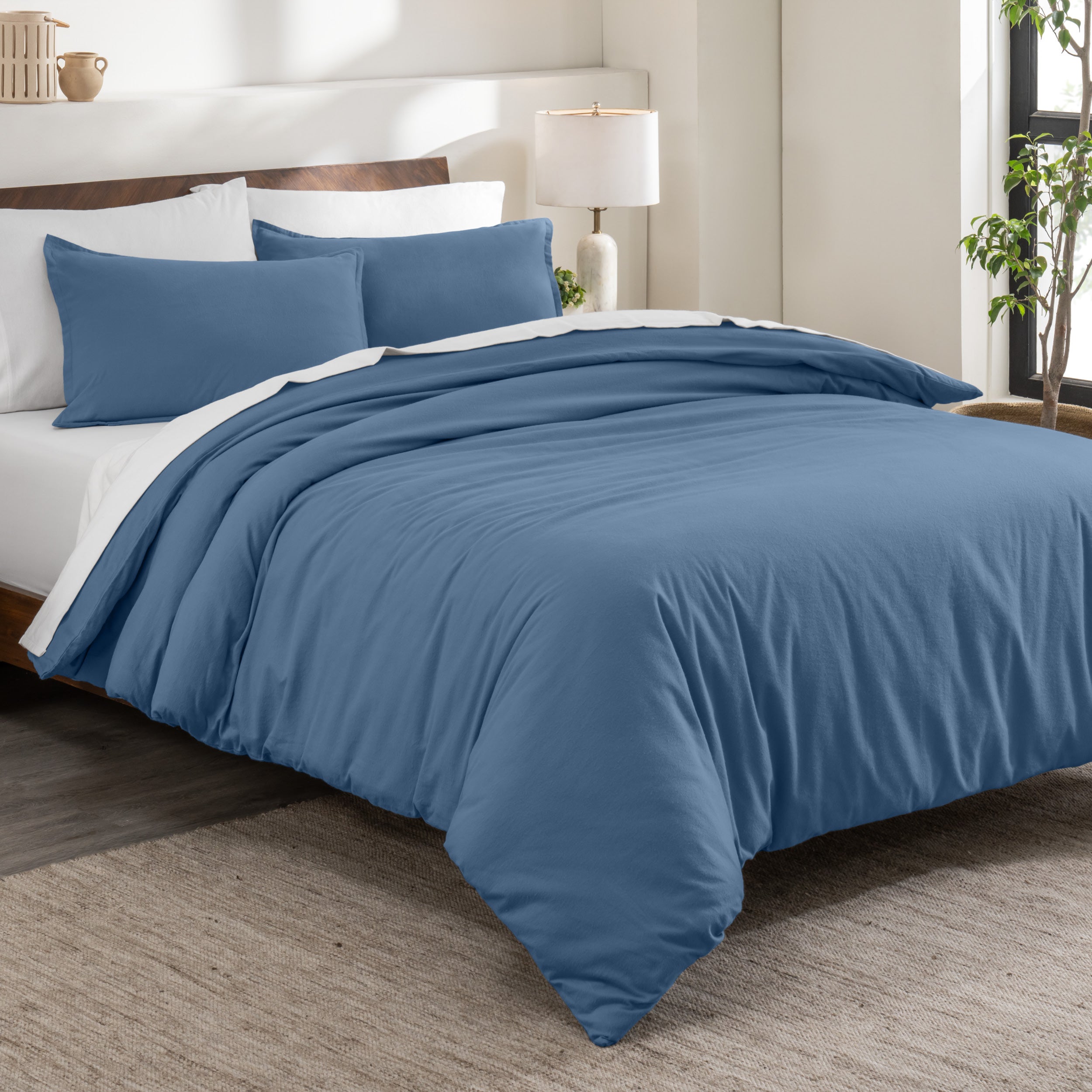 Flannel duvet cover set on a bed in a bedroom with a lamp and plant in the background.