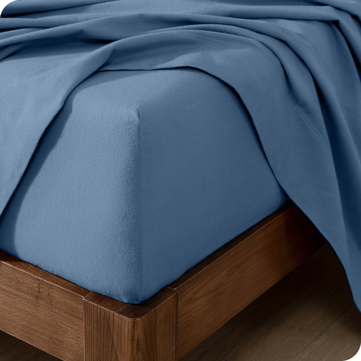 Close up of the corner of a mattress with a flannel fitted sheet and flat sheet on it
