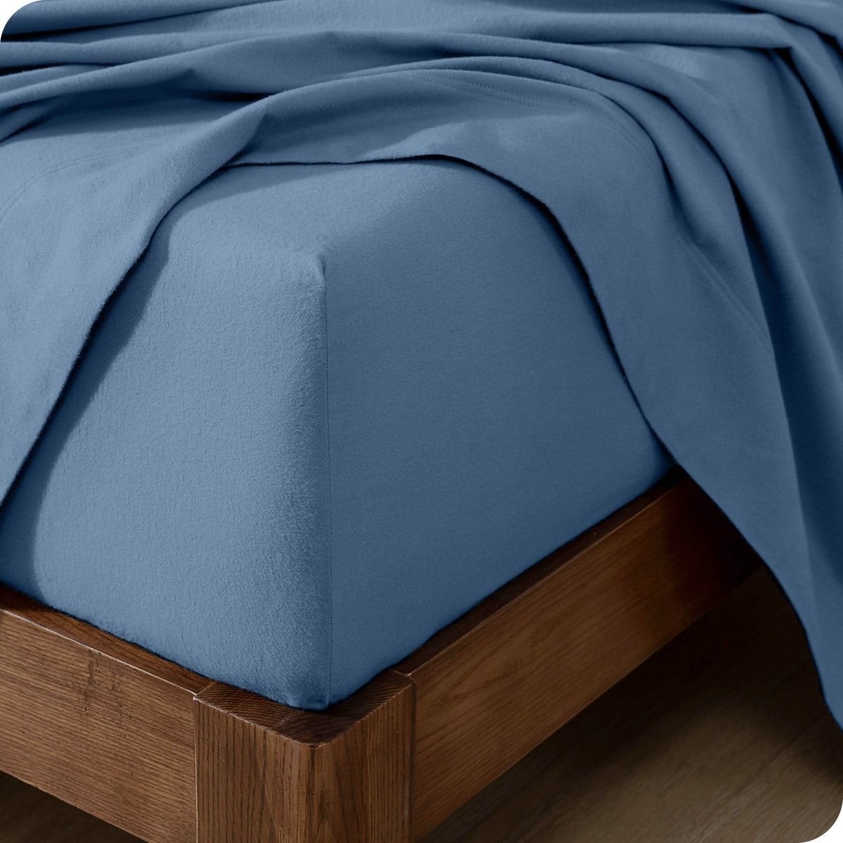 Close up of the corner of a mattress with a flannel fitted sheet and flat sheet on it