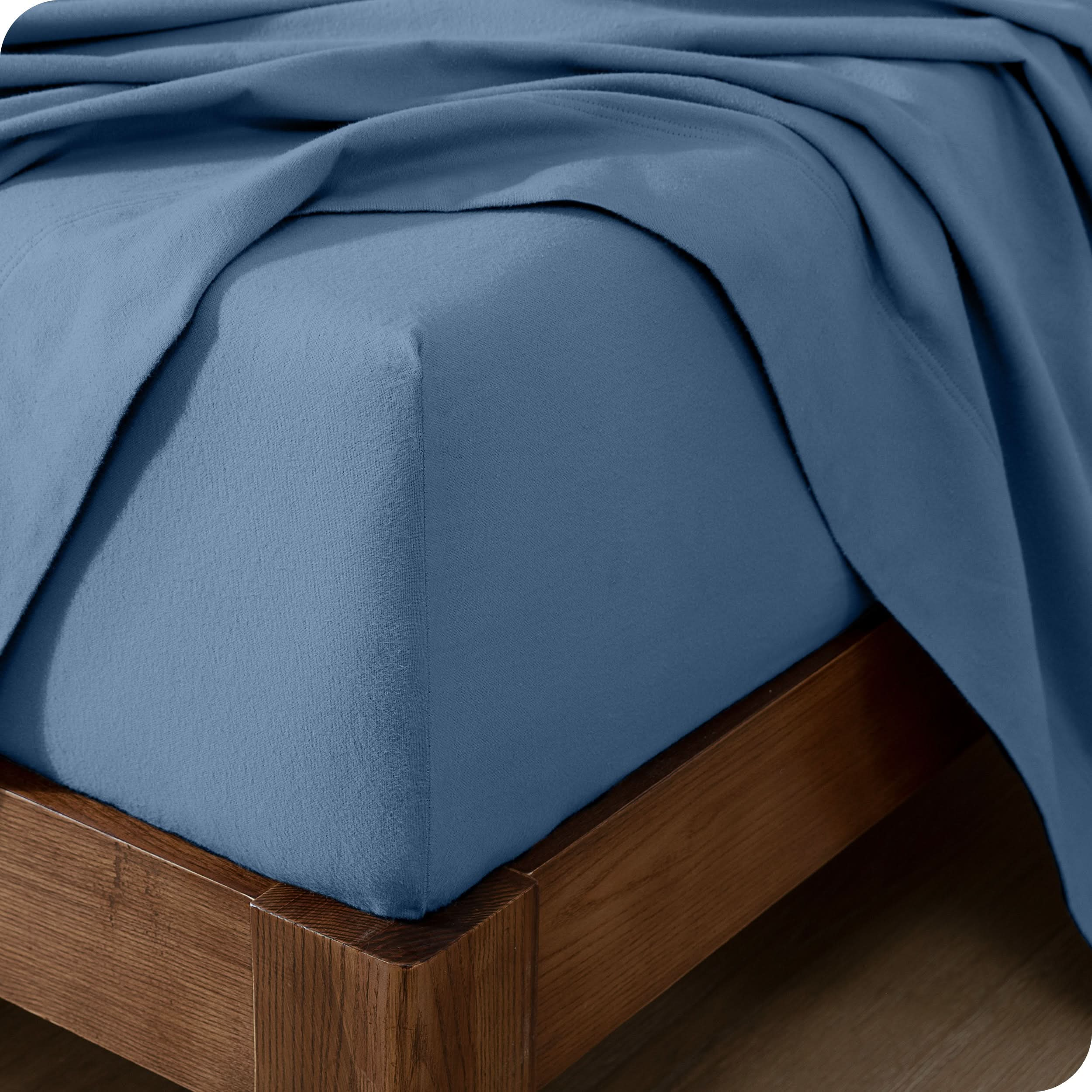 Close up of the corner of a mattress with a flannel fitted sheet and flat sheet on it