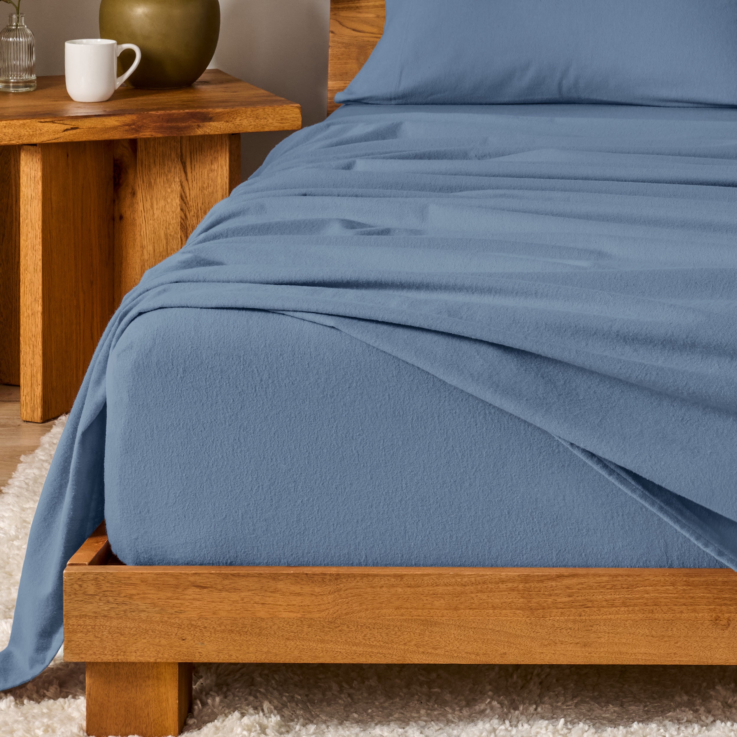 Bed with flannel bedding and wooden headboard and nightstand next to it.