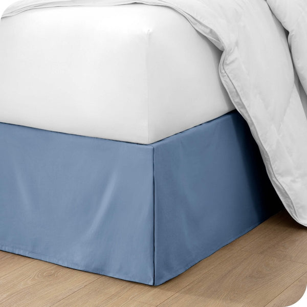 The corner of a bed with a bed skirt and comforter on it