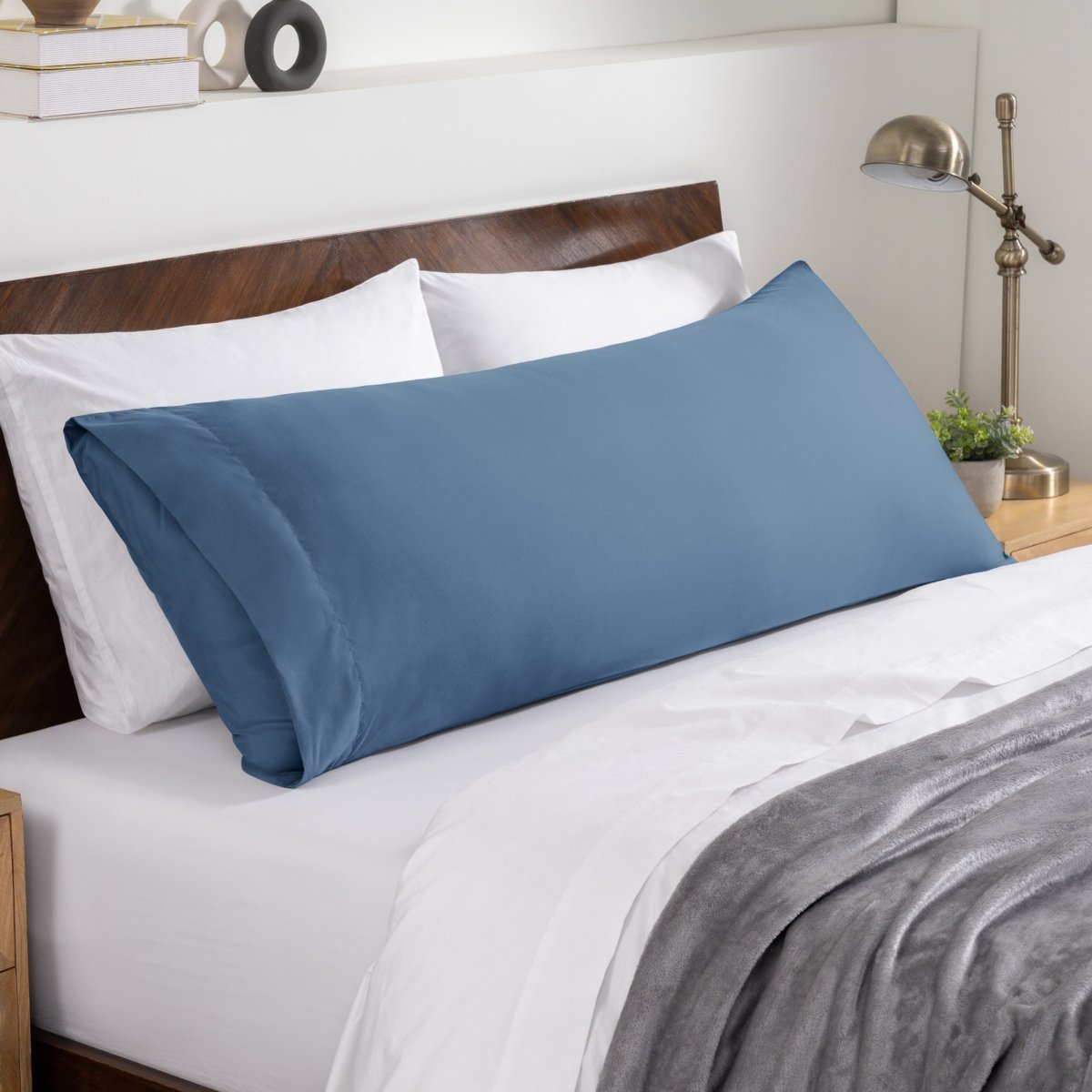 Bed sheets and pillows on a neatly made bed with a wooden headboard.