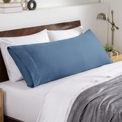 Bed sheets and pillows on a neatly made bed with a wooden headboard.