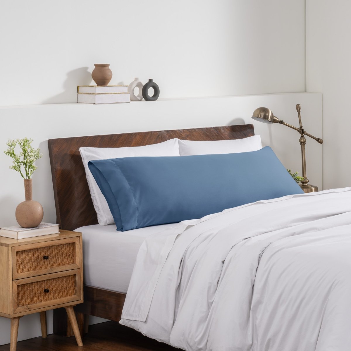 Bedroom with a wooden headboard and white bedding, featuring a nightstand and decorative items.