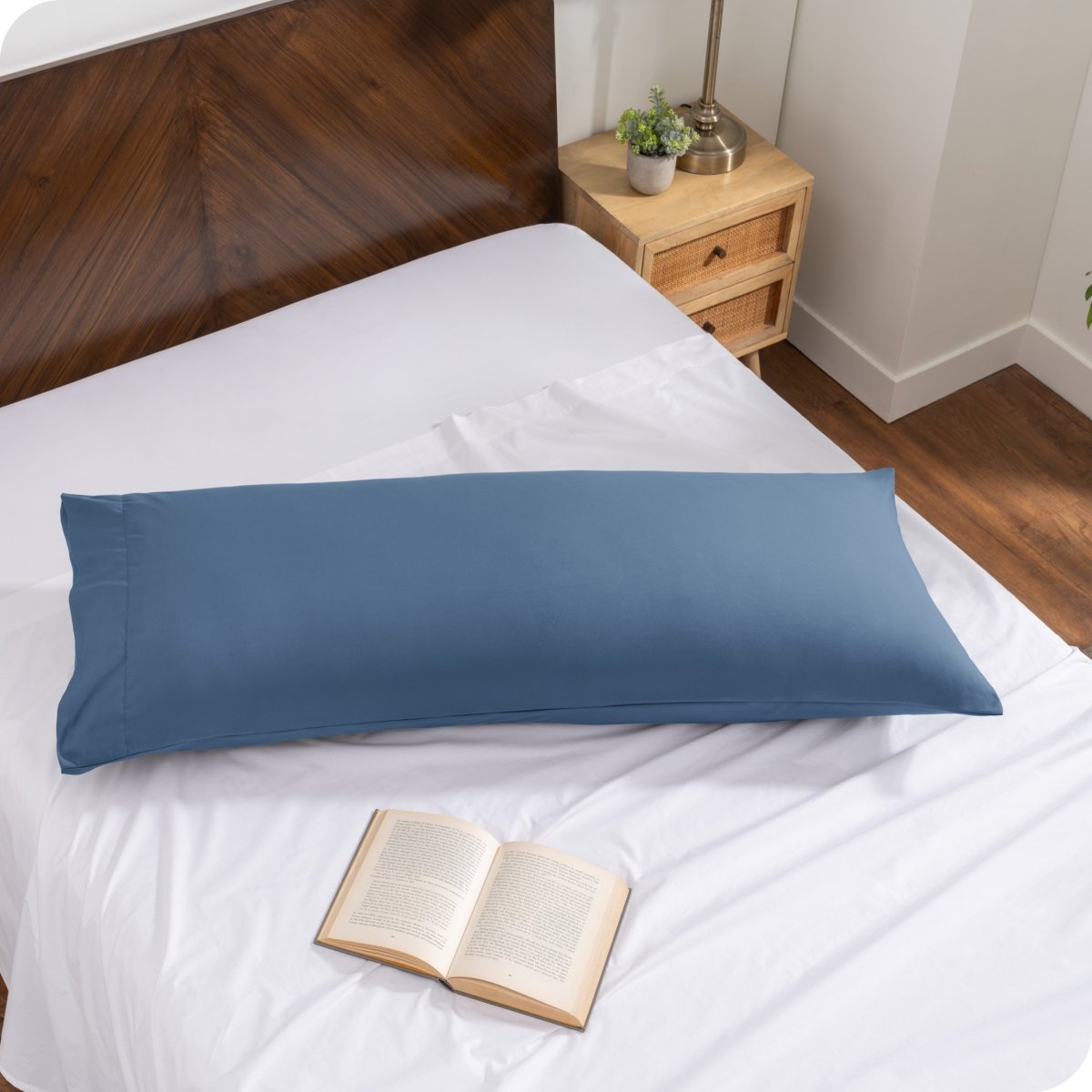 Pillowcase on a body pillow with a wooden headboard and plant in the background