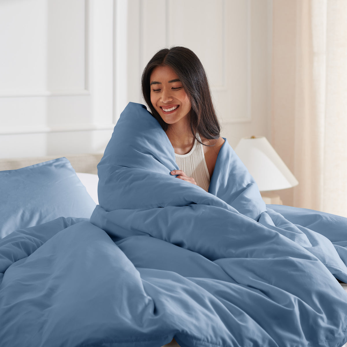 Woman smiling under duvet cover set in a bedroom setting