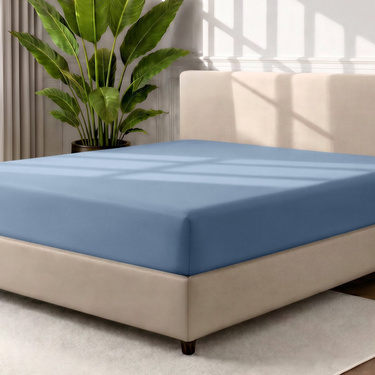 A fitted sheet covering a bed with a cream colored frame, styled in a bedroom setting with a large potted plant.