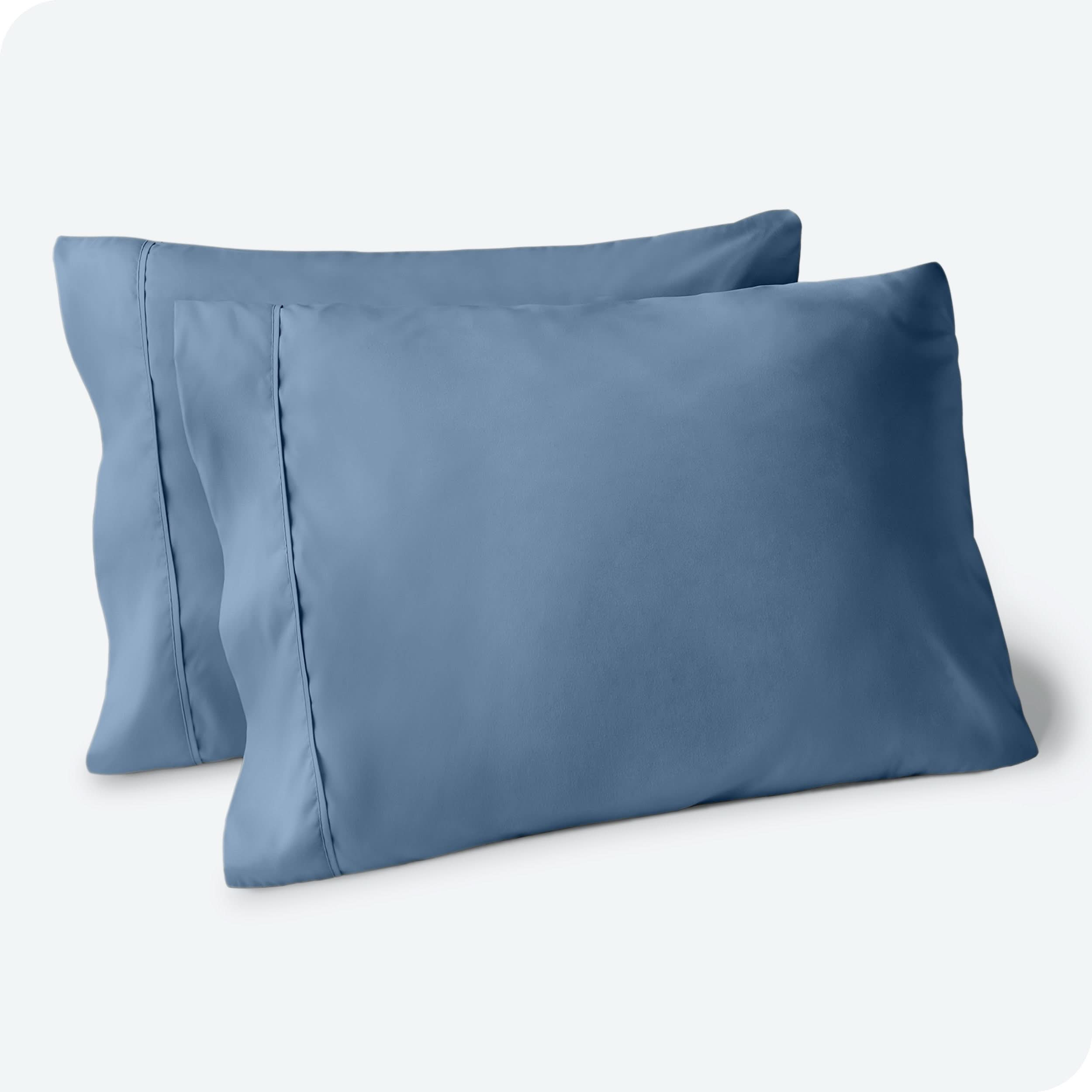 Two pillows on a white background with blue pillowcases on them