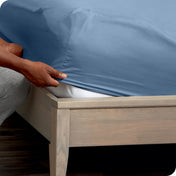 Person adjusting a fitted sheet on a mattress