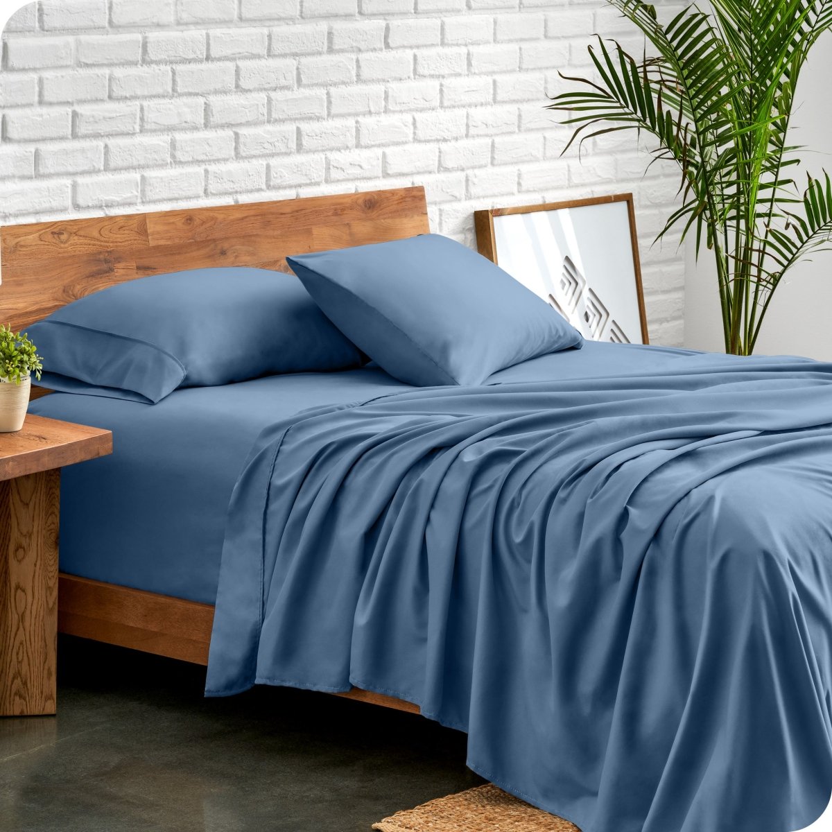 Bed with microfiber sheets against a white brick wall