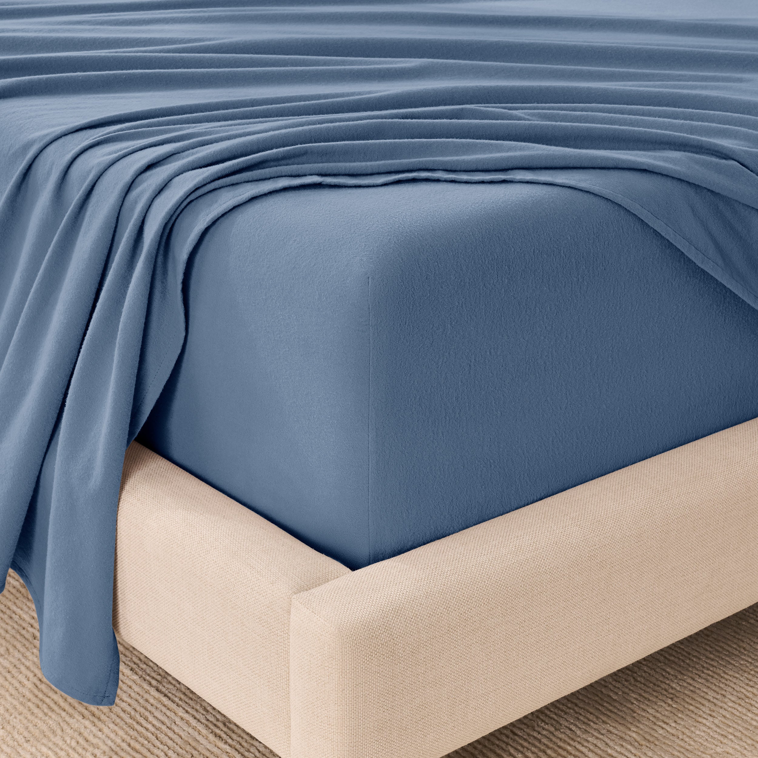 Fitted sheet and top sheet on a mattress with a beige bed frame