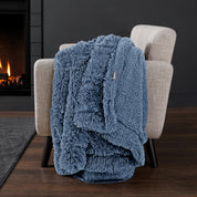 Sherpa blanket draped over an armchair in front of a fireplace.