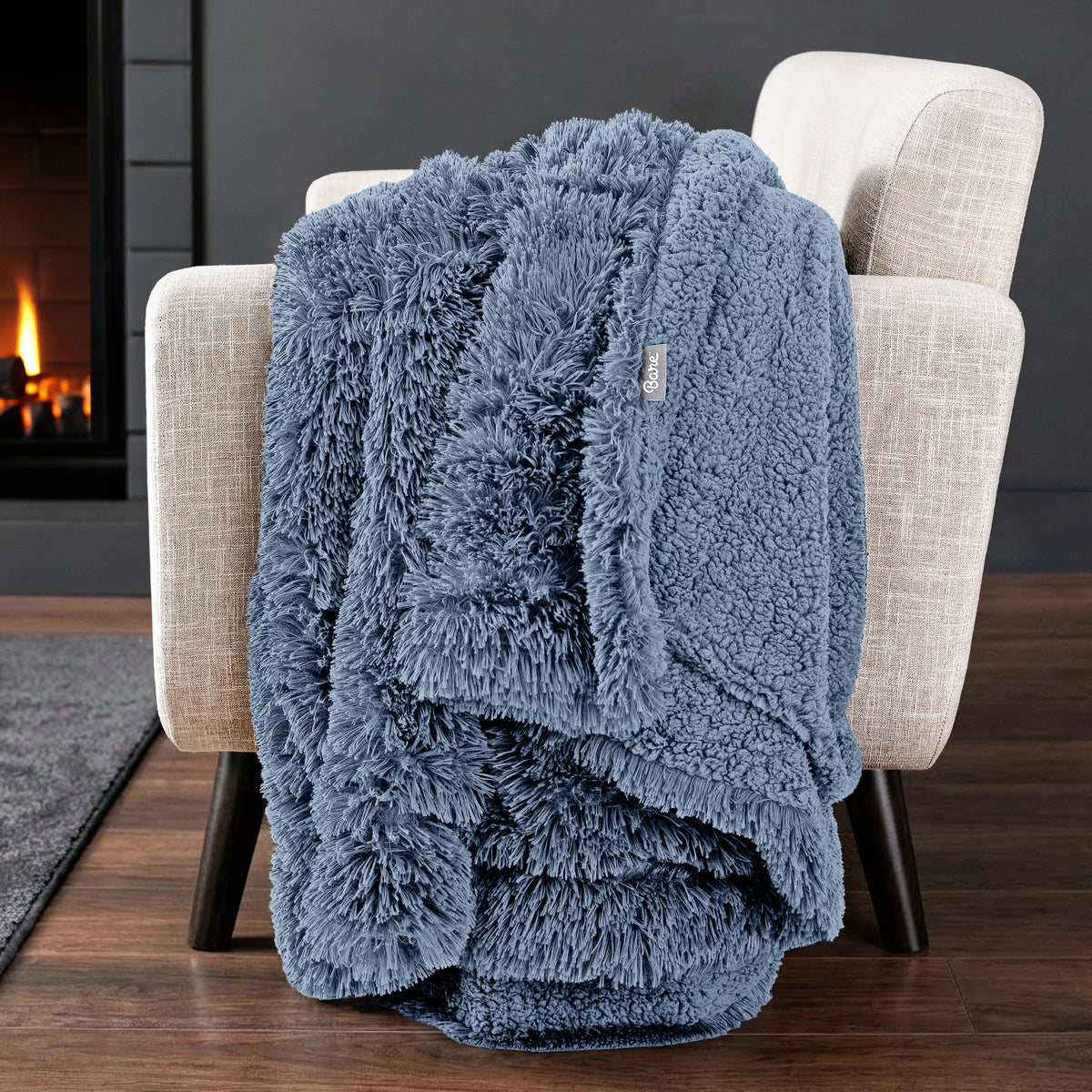 Sherpa blanket draped over an armchair in front of a fireplace.