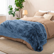 A shaggy faux fur blanket on the end of a bed