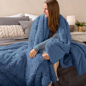 Fluffy blanket draped over a woman sitting on the end of a bed