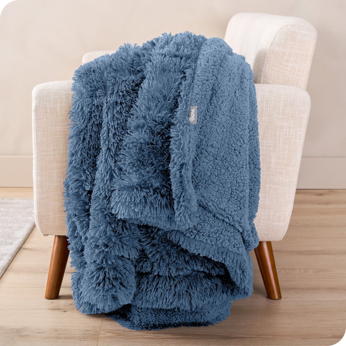 A shaggy faux fur blanket draped over the arm of a chair