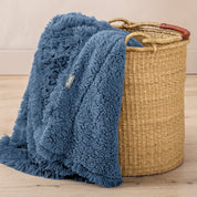 A blanket hanging over the edge of a wicker basket