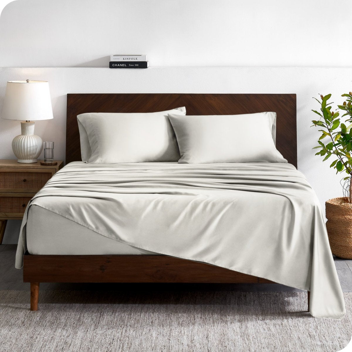 A contemporary bed with a sheet set and a wooden headboard.