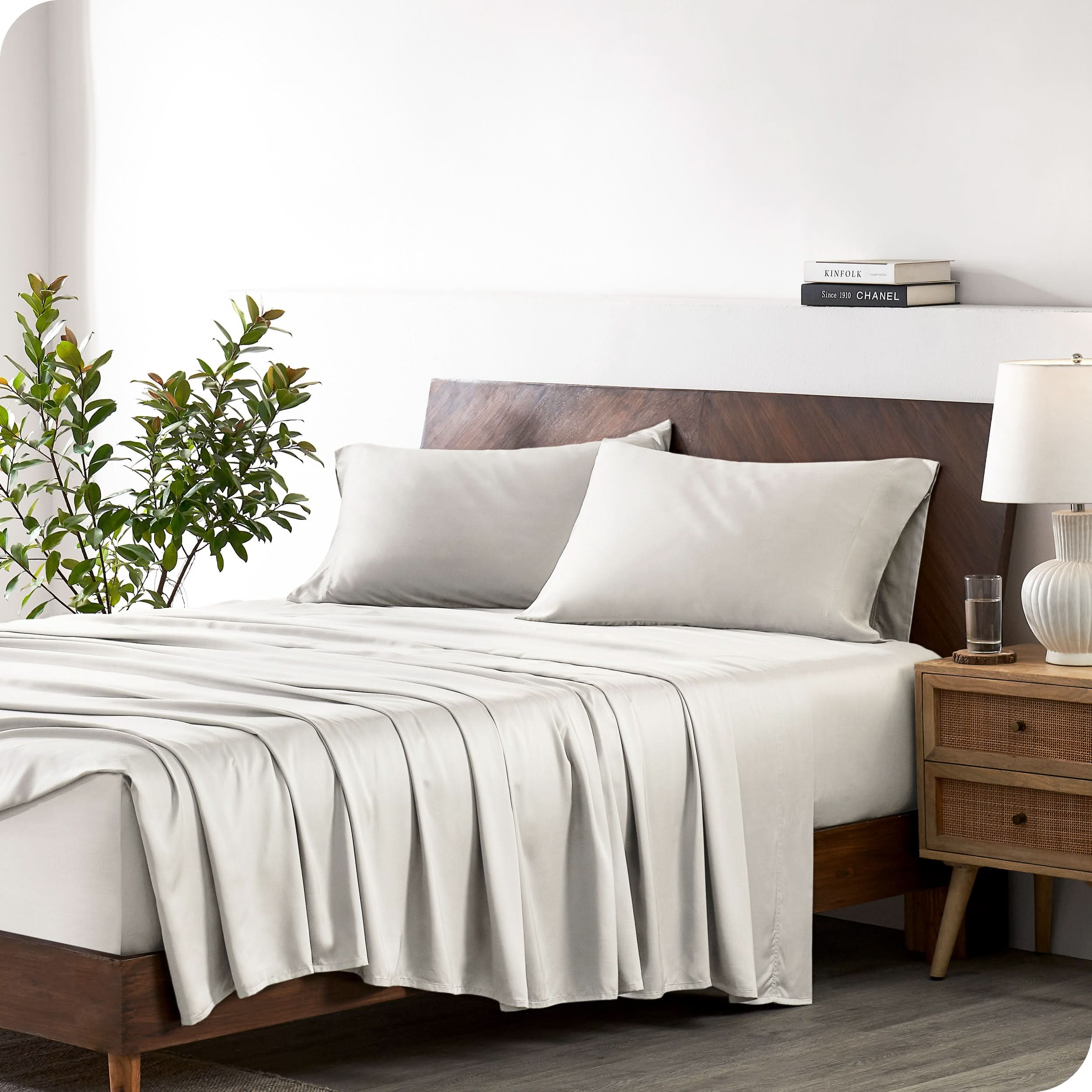 A bamboo sheet set draped over a bed with a wooden bed frame