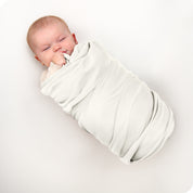 A baby swaddled in a receiving blanket